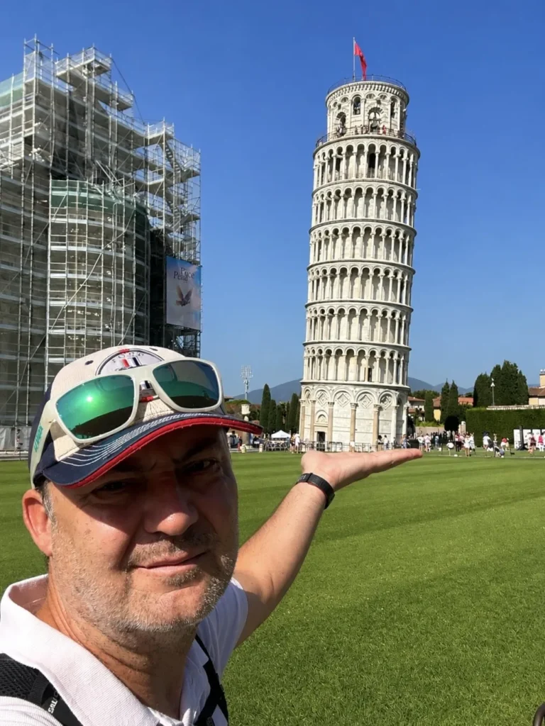 Naklonená veža v Pise v Taliansku – turista pózuje s ikonickou šikmou vežou na dlani počas letnej návštevy.