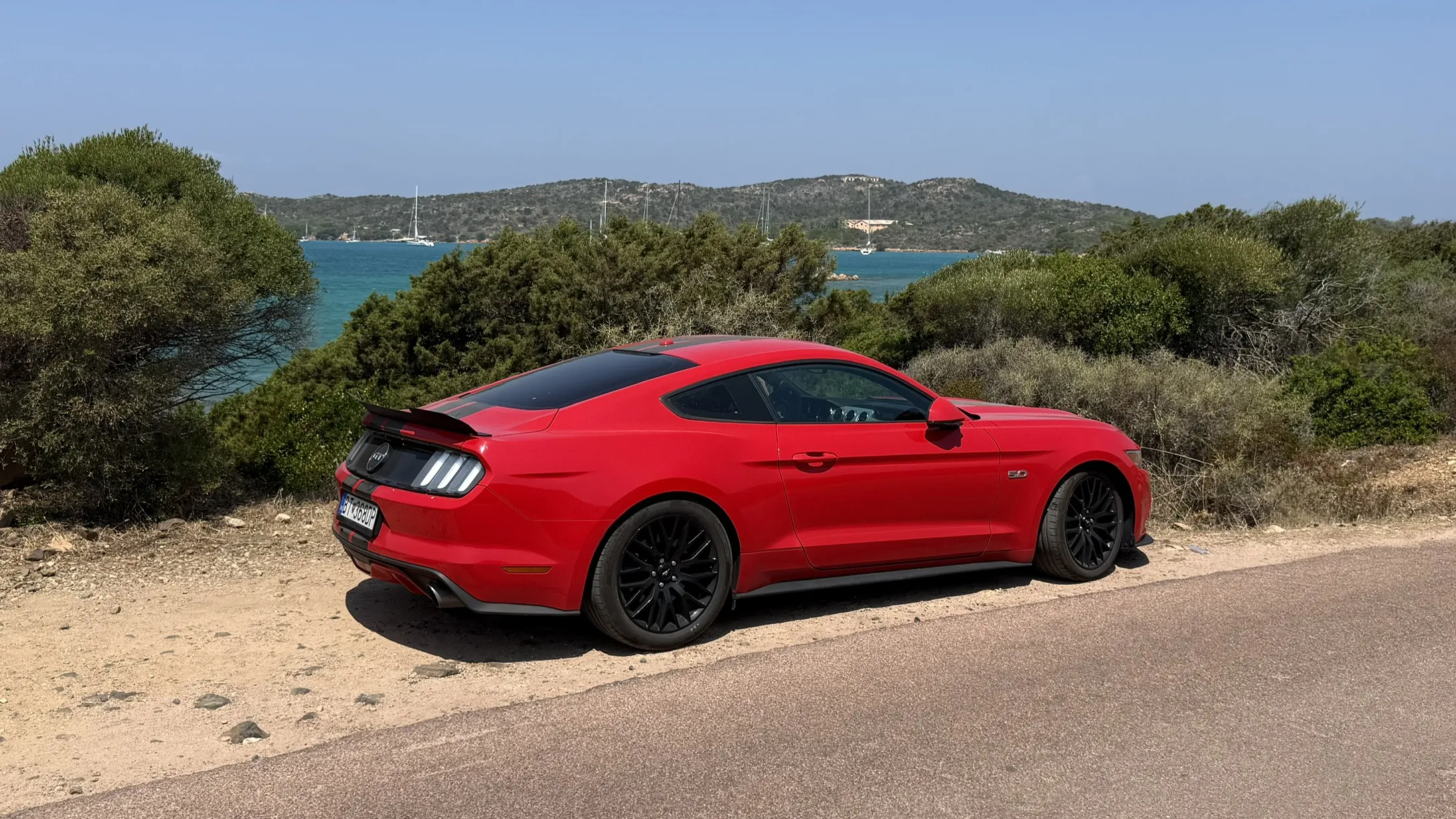 Ford Mustang zaparkovaný pri pobreží Sardínie počas roadtripu autom na Sardíniu cez Taliansko.